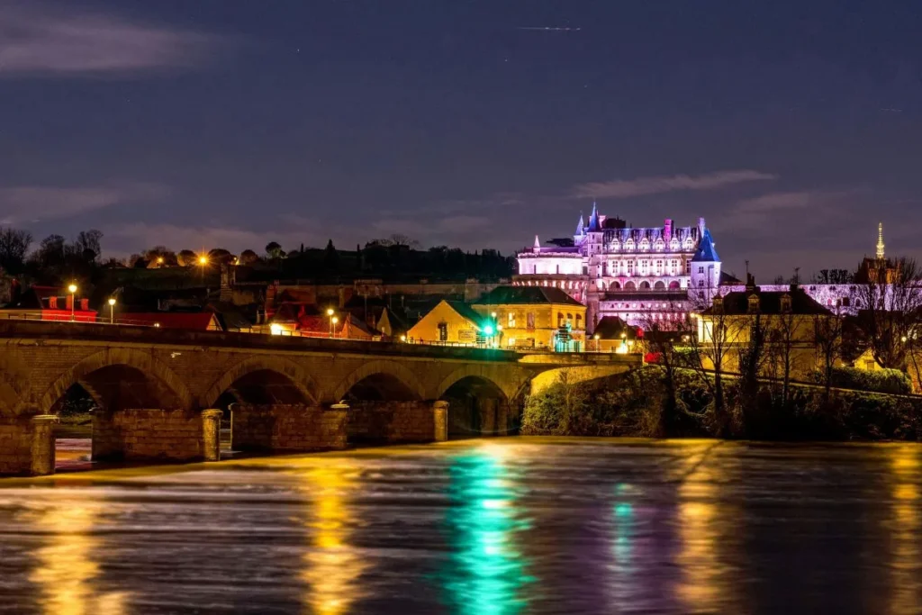 Vue nocturne du Château Royal d’Amboise illuminé avec le pont et les reflets sur la Loire